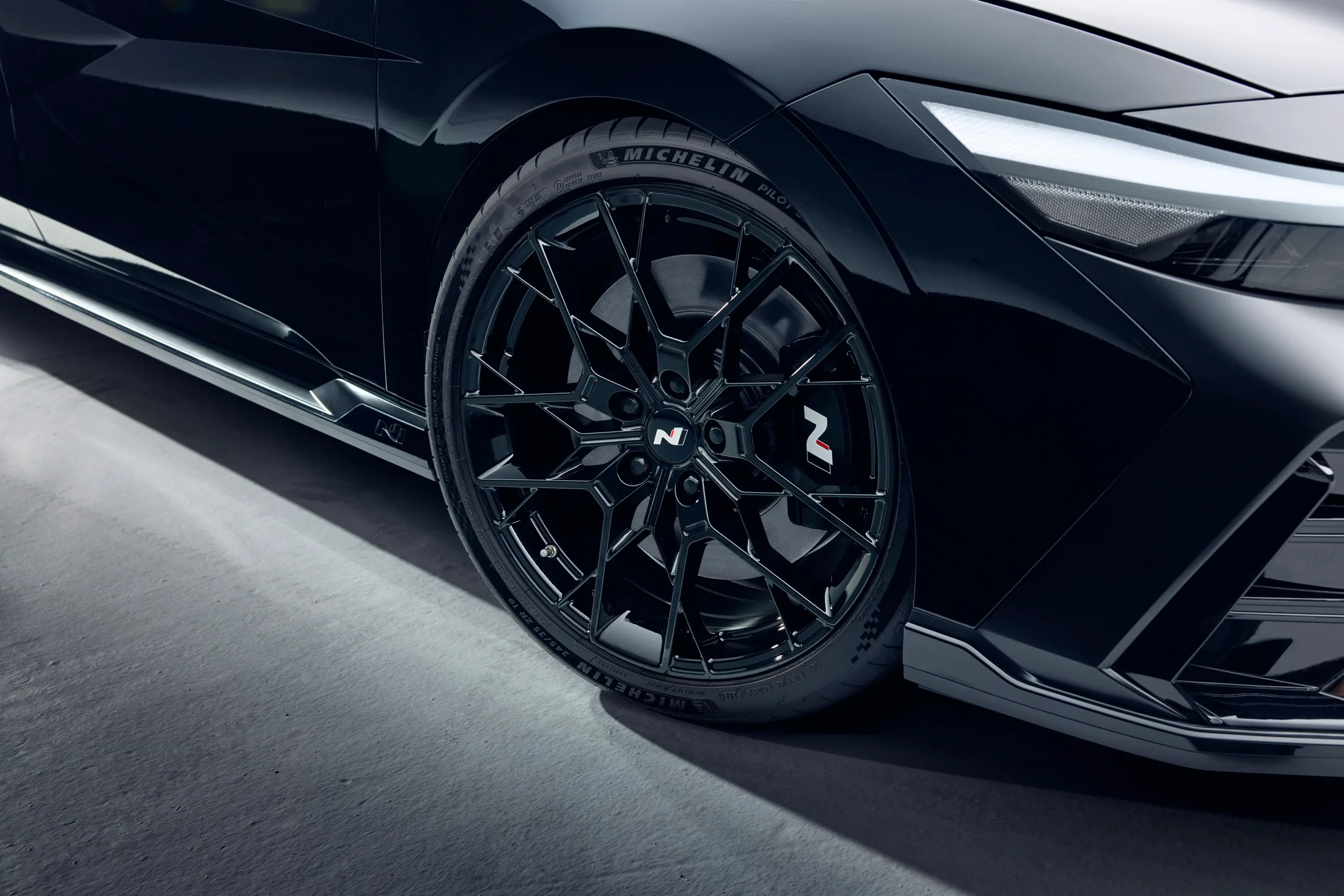 Monochrome forged wheel and front-quarter detail.